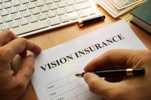 A man signs a vision insurance form to receive vision benefits in eyecare office.