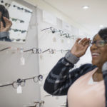 Smiling woman trying on eyeglasses in optometry shop