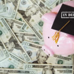 piggy with In Debt graduation cap on money