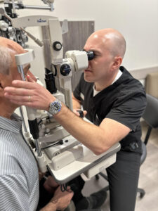 An optometrist examines a patient in an exam room in his office.