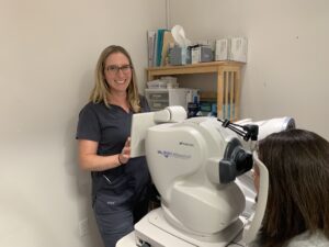An optometrist stands next to her Maestro2 Robotic OCT and Color Fundus Camera from Topcon Healthcare.